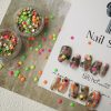 Colorful press-on nails with vibrant designs, featuring pink, orange, and neon green accents, displayed on a card from EasyPressOn.com : Tiiti Ho Nail Studio.