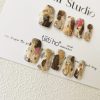 Artistic press-on nails with a gold and brown marble design, displayed on a white card from Tiiti Ho Nail Studio.