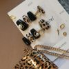 Chic press-on nails with black and leopard print design, featuring gold and pearl accents, displayed on a card from EasyPressOn.com : Tiiti Ho Nail Studio.