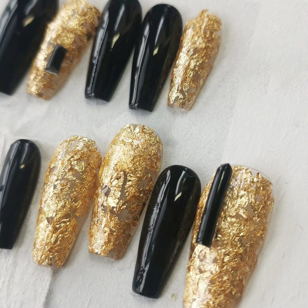 Luxurious press-on nails with a black and gold foil design, displayed on a card from EasyPressOn.com : Tiiti Ho Nail Studio.
