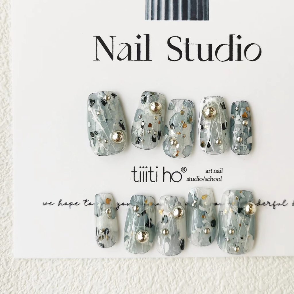 Artistic press-on nails with a silver and grey design, featuring metallic accents, displayed on a white card from EasyPressOn.com : Tiiti Ho Nail Studio.