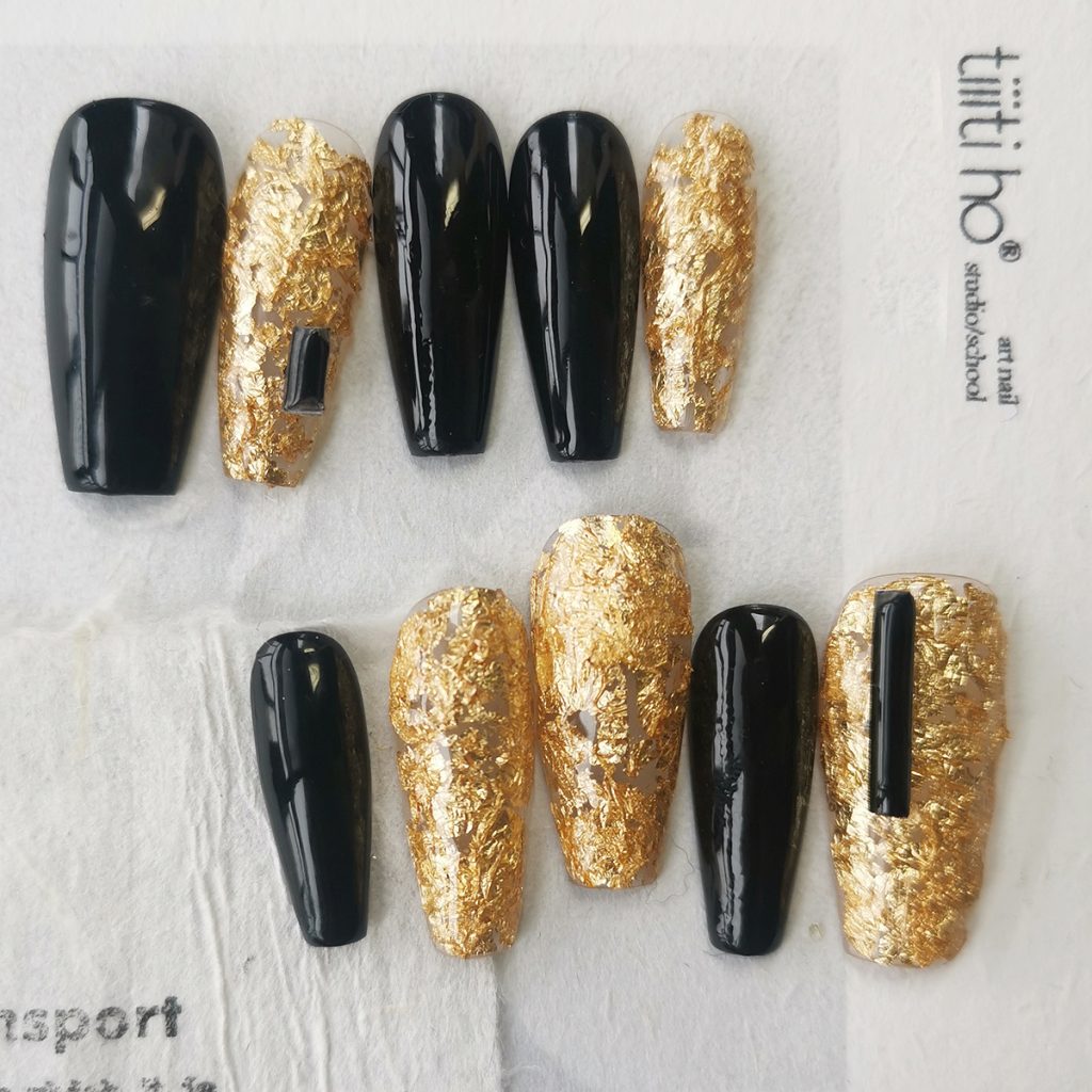 Luxurious press-on nails with a black and gold foil design, displayed on a card from EasyPressOn.com : Tiiti Ho Nail Studio.