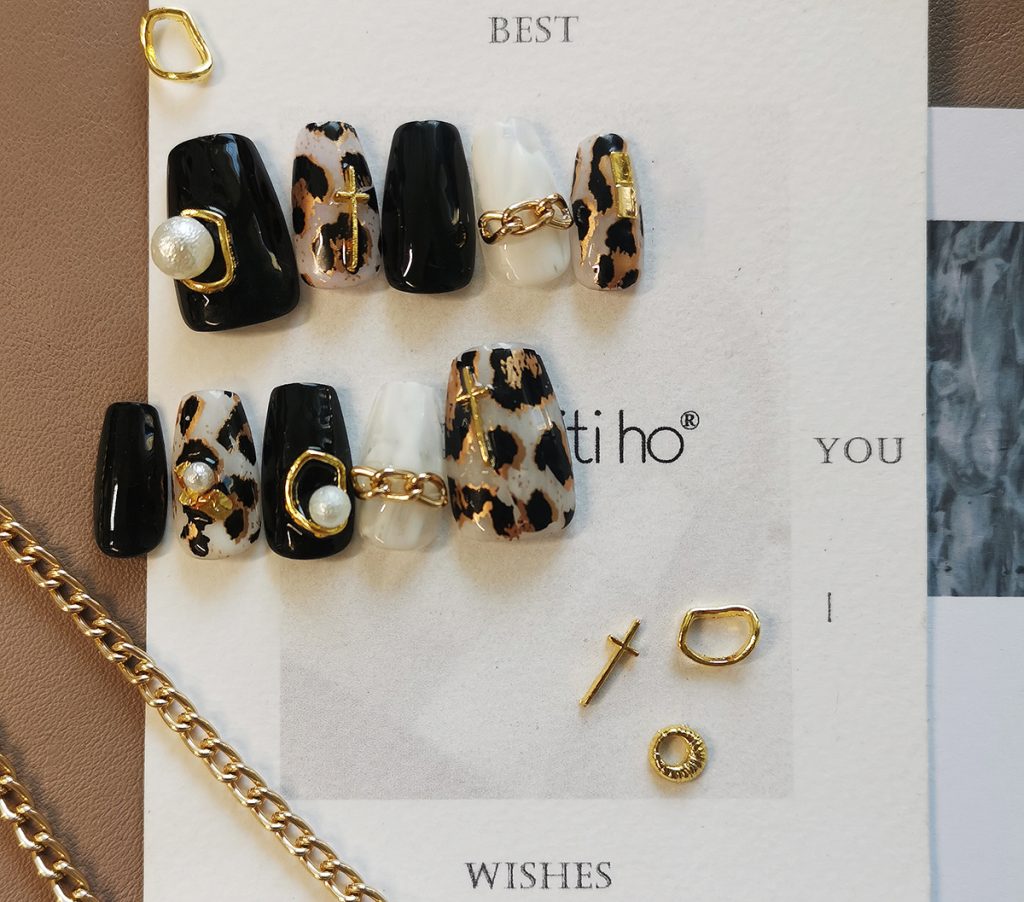 Chic press-on nails with black and leopard print design, featuring gold and pearl accents, displayed on a card from EasyPressOn.com : Tiiti Ho Nail Studio.