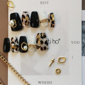 Chic press-on nails with black and leopard print design, featuring gold and pearl accents, displayed on a card from EasyPressOn.com : Tiiti Ho Nail Studio.