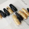 Luxurious press-on nails with a black and gold foil design, displayed on a card from EasyPressOn.com : Tiiti Ho Nail Studio.